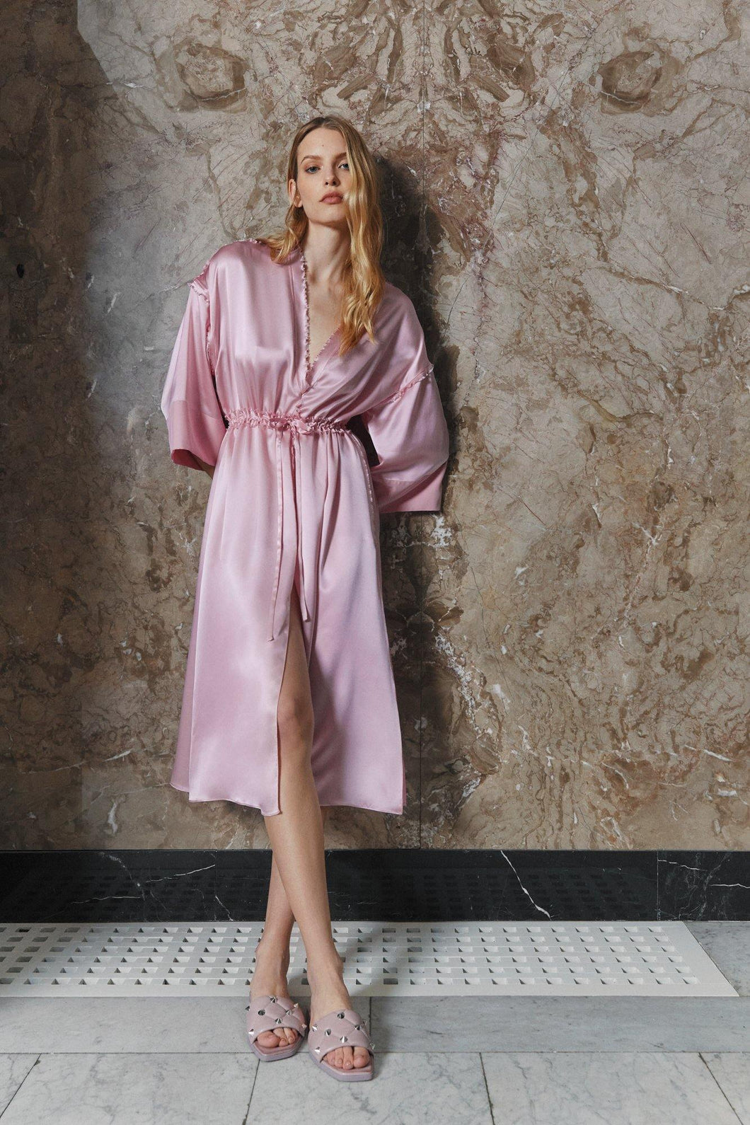 Blonde model wearing pure silk satin kimono dress Anatolé in pink color. Side view. Brand Nynolia