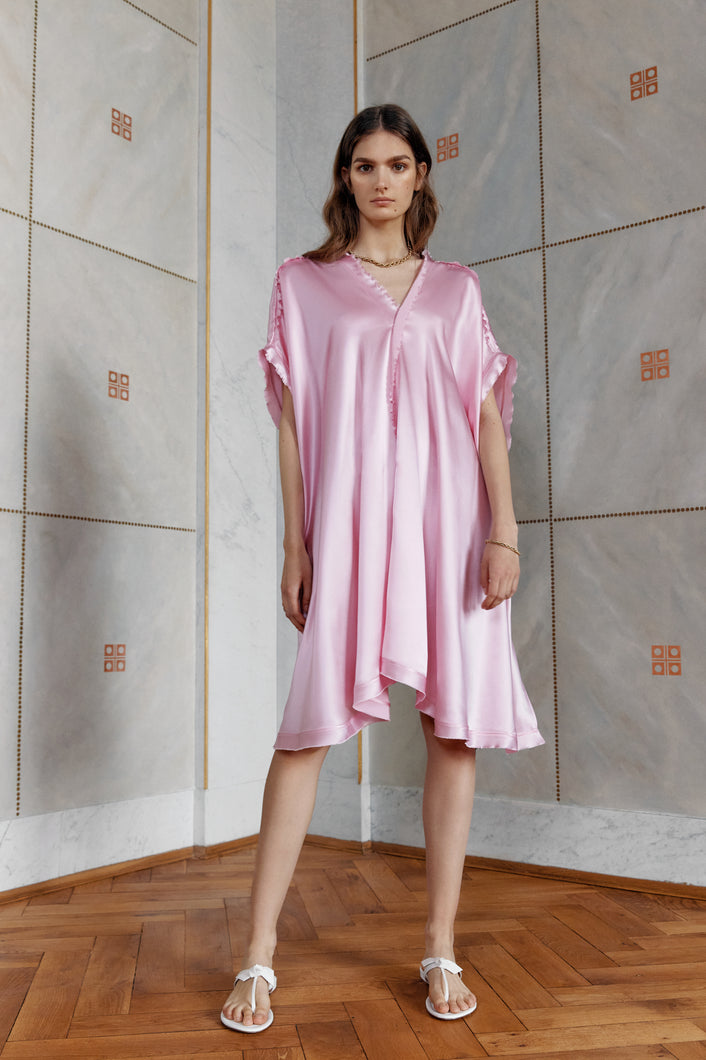 Brunette beauty wearing satin silk kaftan dress Springs in pink color front view